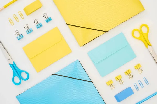 Posa piatta di cartelle blu e giallo, buste, forbici, matite, gomme e graffette isolate su bianco — Foto stock