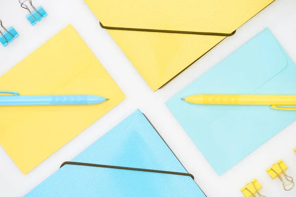 Плоский шар синьо-жовтих папок, конвертів, паперових затискачів і ручок ізольований на білому — стокове фото