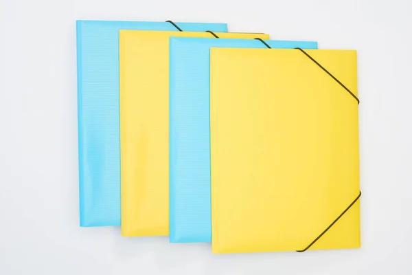 Pose plate de dossiers jaunes et bleus isolés sur blanc — Photo de stock