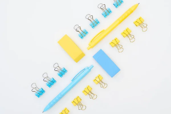 Flat lay of yellow and blue erasers, pens and paper clips isolated on white — Stock Photo