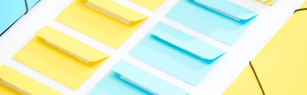 Panoramic shot of yellow and blue folders and opened envelopes on white background — Stock Photo