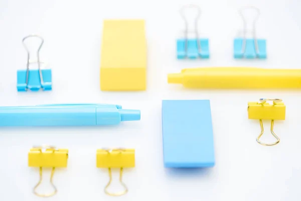 Selective focus of yellow and blue pencils, erasers and paper clips on white background — Stock Photo