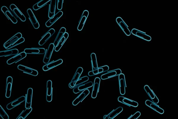 Top view of blue scattered paper clips isolated on black — Stock Photo