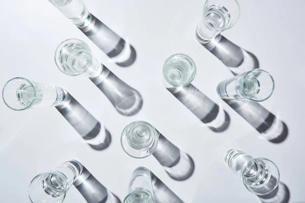 Vista superior de vasos transparentes con agua sobre fondo blanco con sombras - foto de stock