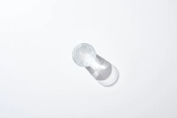 Vue de dessus du verre transparent avec de l'eau sur la surface blanche avec ombre — Photo de stock