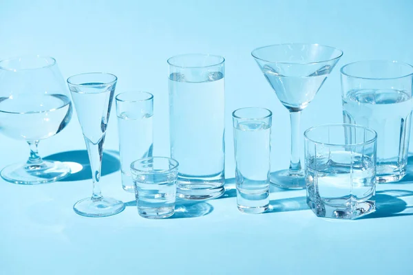 Transparent glasses with clear water on blue background — Stock Photo