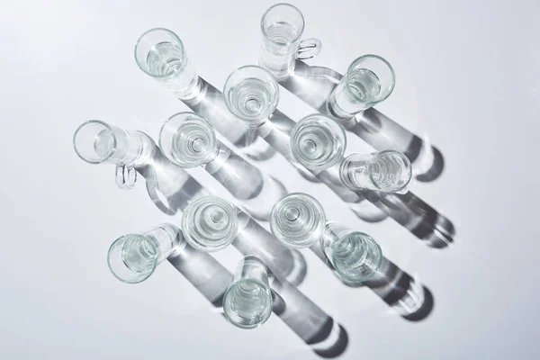 Top view of glasses with clear water and shadows on white surface — Stock Photo