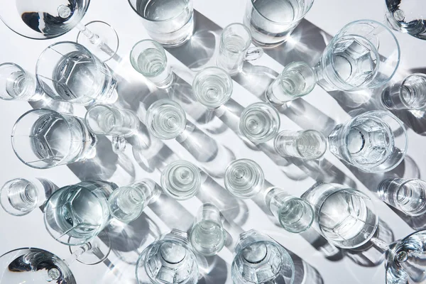 Draufsicht auf Gläser mit reinem Wasser und Schatten auf weißer Oberfläche — Stockfoto