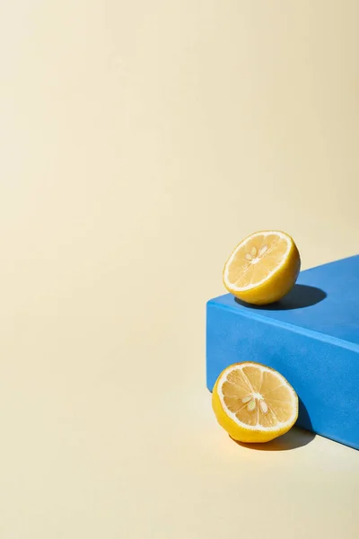 Bright lemon halves and blue cube on beige background — Stock Photo