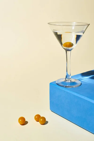 Vetro trasparente con cocktail su cubo blu su sfondo beige — Foto stock