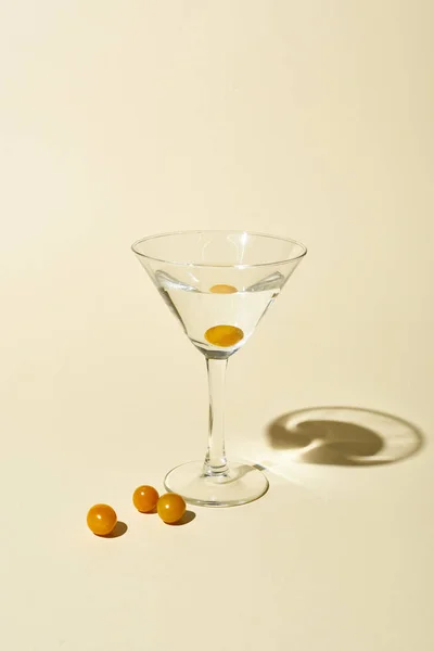 Transparent glass with cocktail and berries on beige background — Stock Photo