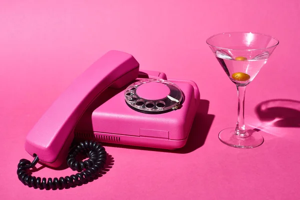 Cóctel con teléfono rosa brillante de oliva y retro sobre fondo rosa - foto de stock