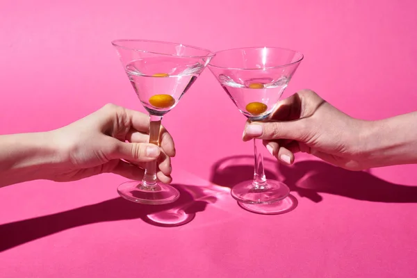 Vista recortada de las mujeres sosteniendo vasos con cócteles sobre fondo rosa - foto de stock