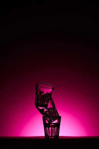 Pirámide de gafas sobre fondo oscuro con iluminación rosa — Stock Photo