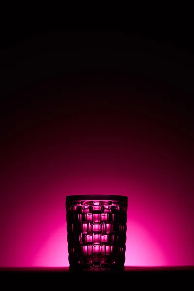 Transparentes strukturiertes Glas auf dunklem Hintergrund mit rosa Beleuchtung — Stockfoto