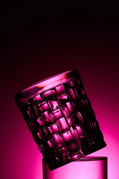 Close up view of transparent textured glass on dark background with pink illumination — Stock Photo