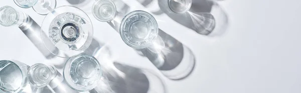 Plano panorámico de vidrios transparentes con agua clara sobre fondo blanco con espacio para copiar — Stock Photo