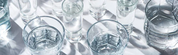 Vista de cerca de vasos transparentes con agua sobre fondo blanco, plano panorámico - foto de stock