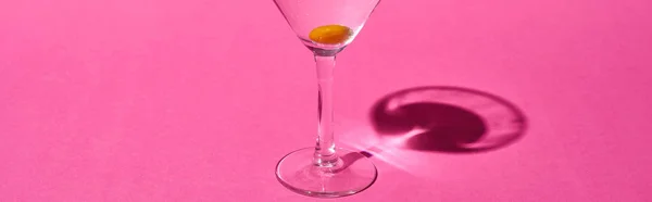 Tiro panorâmico de vidro transparente com coquetel e azeitona sobre fundo rosa — Fotografia de Stock