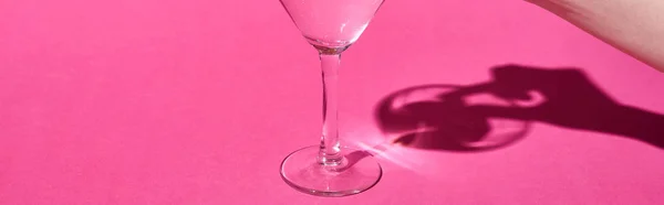 Vista cortada de mulher colocando azeitona em vidro com coquetel no fundo rosa, tiro panorâmico — Fotografia de Stock