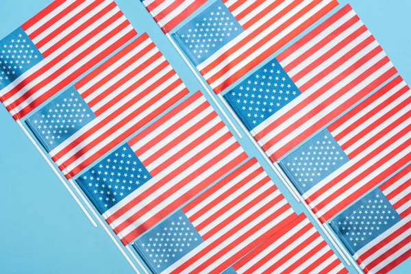 Tendido plano con banderas americanas en palos sobre fondo azul - foto de stock