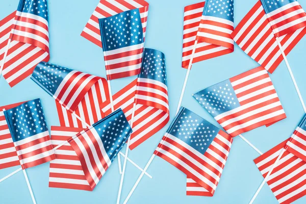 Вид зверху на американські прапори на палицях, розкиданих на синьому фоні — стокове фото