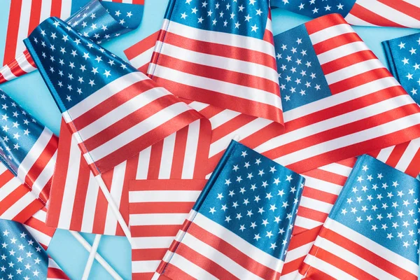 Vista superior de banderas nacionales americanas sobre palos dispersos sobre fondo azul - foto de stock
