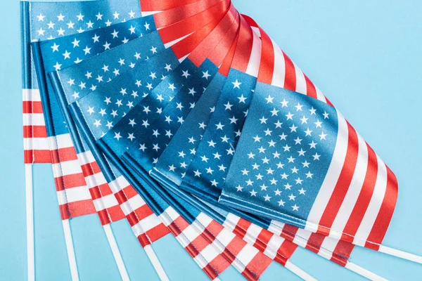 Vista de cerca de banderas americanas de seda en palos sobre fondo azul - foto de stock
