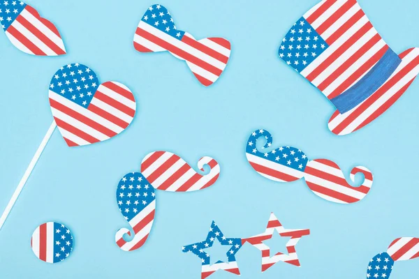 Top view of paper cut decorative mustache, glasses, hat and heart made of usa flags on blue background — Stock Photo