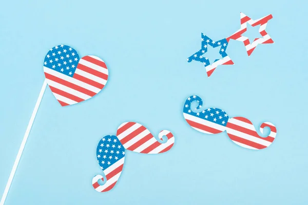 Top view of paper cut decorative glasses, mustache and heart made of american flags on blue background — Stock Photo