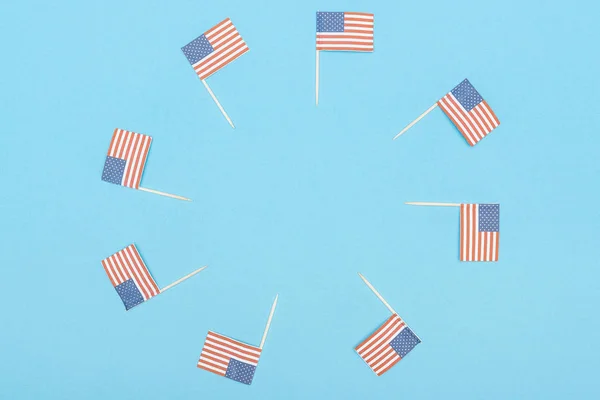 Cadre rond en papier découpé drapeaux américains décoratifs sur bâtons de bois sur fond bleu avec espace de copie — Photo de stock
