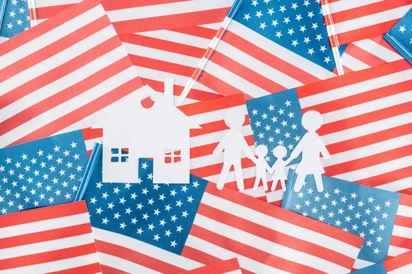 Vue du haut de la maison en papier blanc et de la famille sur fond de drapeaux américains — Photo de stock