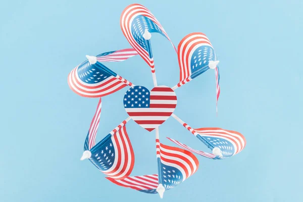 Vista superior de banderas americanas en círculo con corazón sobre fondo azul - foto de stock