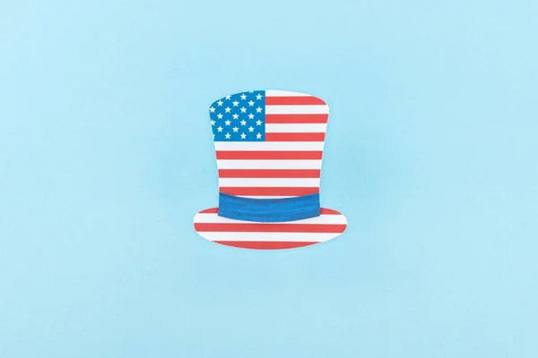 Вид зверху на паперовий вирізаний декоративний капелюх з американського прапора на синьому фоні — стокове фото