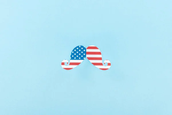 Вид зверху на паперові вирізані декоративні вуса з американського прапора на синьому фоні — стокове фото