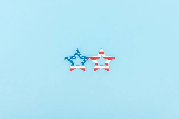 Вид зверху на паперові вирізані декоративні окуляри з американського прапора на синьому фоні — стокове фото