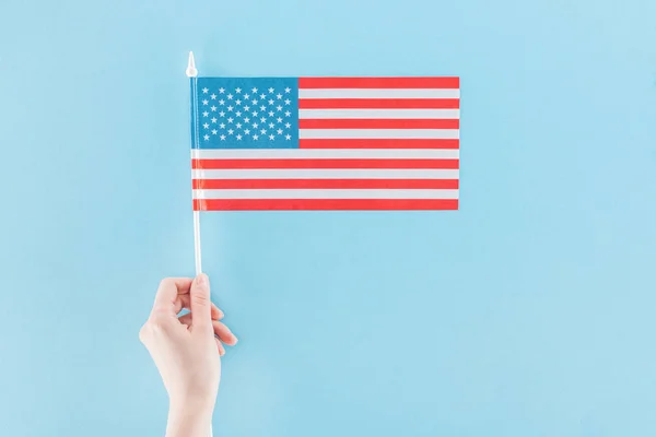 Cropped view of woman holding national american flag on stick on blue background — Stock Photo