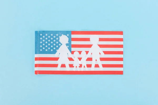 Vista superior da família branca de corte de papel na bandeira nacional americana no fundo azul — Fotografia de Stock
