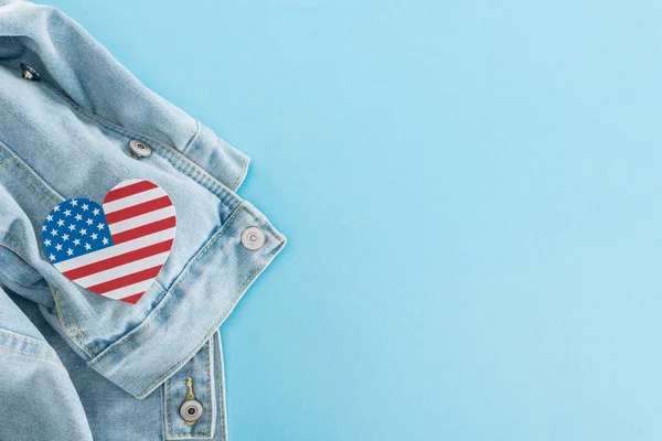 Vue du haut du coeur de papier coupé en drapeau américain sur denim veste élégante sur fond bleu avec espace de copie — Photo de stock