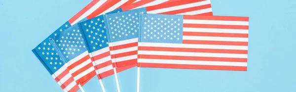 Plano panorámico de banderas americanas sobre palos sobre fondo azul - foto de stock