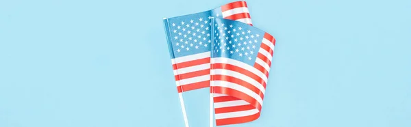 Plano panorámico de banderas de EE.UU. en palos sobre fondo azul - foto de stock