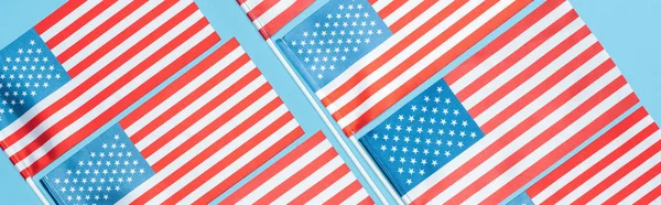 Piatto giaceva con bandiere americane su bastoni su sfondo blu, colpo panoramico — Foto stock