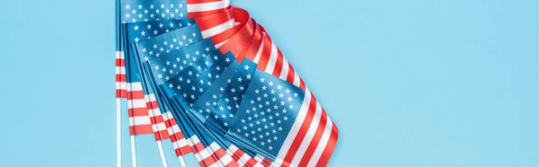 Панорамный снимок глянцевых американских флагов на палочках на синем фоне — стоковое фото