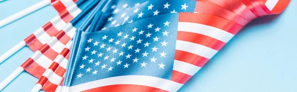 Vista de cerca de banderas de seda EE.UU. en palos sobre fondo azul, tiro panorámico - foto de stock