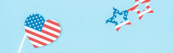 Plano panorámico de vasos cortados en papel y corazón hecho de banderas de EE.UU. sobre fondo azul - foto de stock