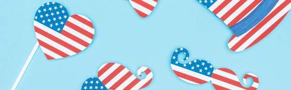 Plano panorámico de papel corte bigote decorativo, sombrero y corazón hecho de banderas de EE.UU. sobre fondo azul - foto de stock
