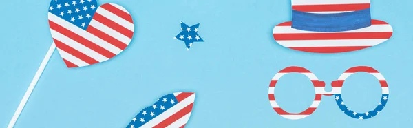 Panoramic shot of paper cut decorative glasses, hat, lips, star and heart made of usa flags on blue background — Stock Photo