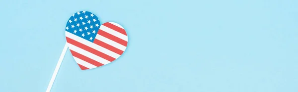 Vista superior del corazón decorativo de corte de papel en palo de bandera americana sobre fondo azul, plano panorámico - foto de stock