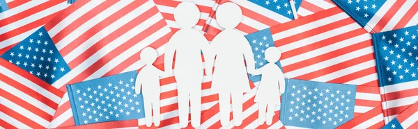 Panoramic shot of white paper cut family on american flags background — Stock Photo