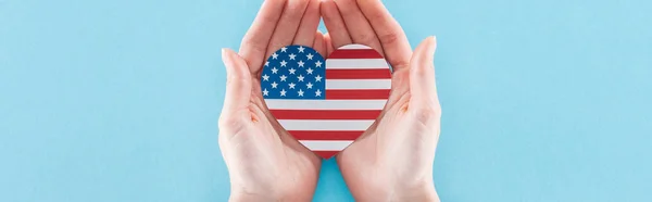 Visão parcial da mulher segurando coração feito de bandeira americana nacional em fundo azul, tiro panorâmico — Fotografia de Stock